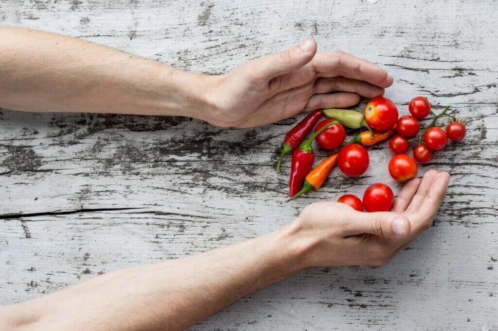 Hand som tar tomater och paprika